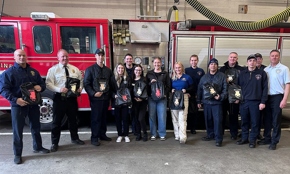 Members of the West Springfield Fire Department and Ӱֱapp OTD students pose for a photo with BEary Bags in front of a fire engine at the WSFD station.